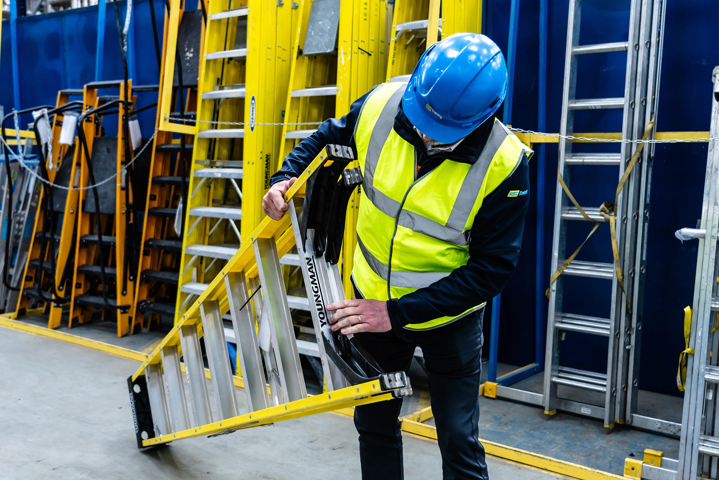 Man in helmet pointing out faults on a yellow ladder on a training course